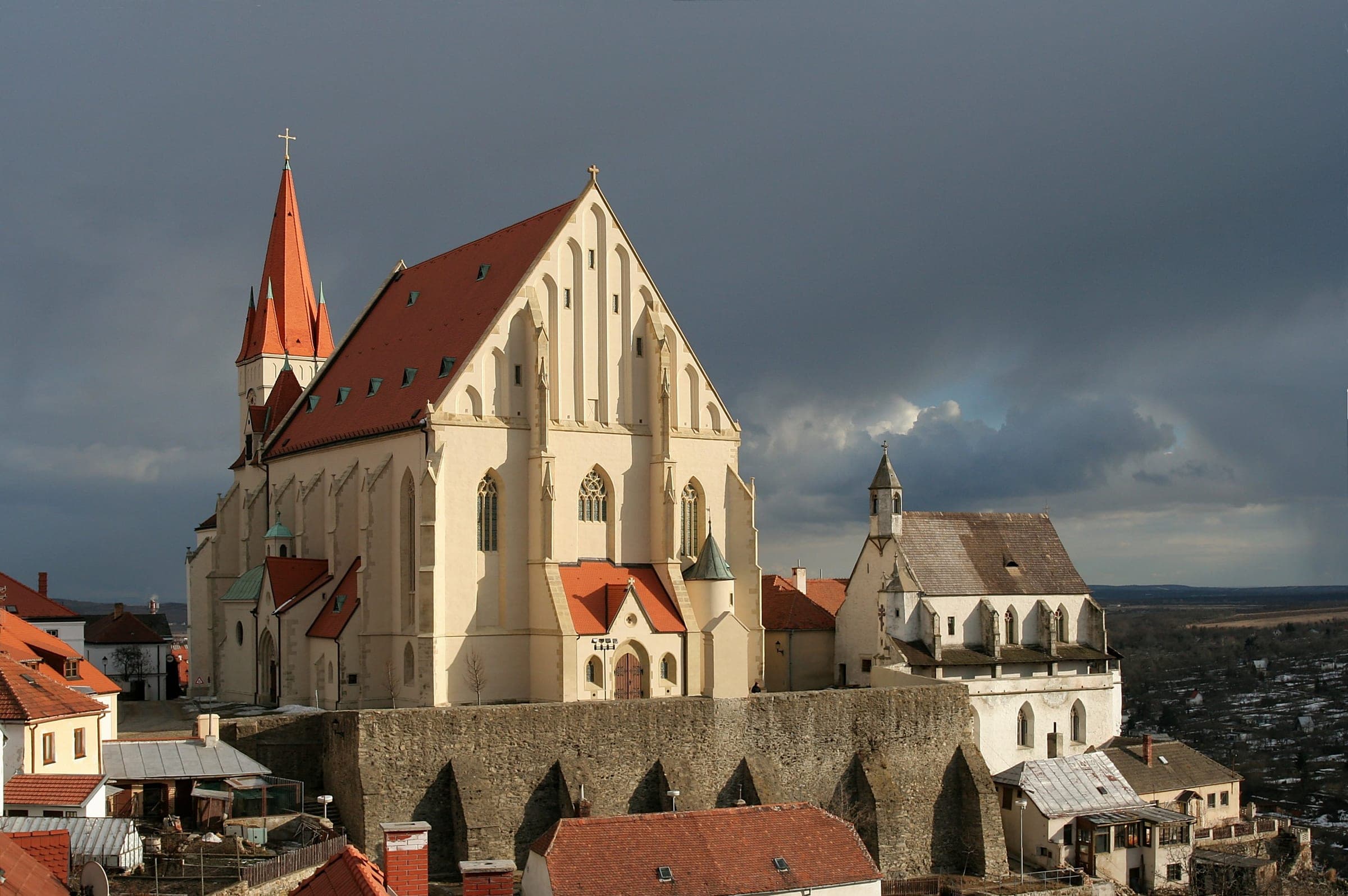 Kostel sv. Mikuláše a Svatováclavská kaple nad hradbami Znojma pod bouřkovou oblohou