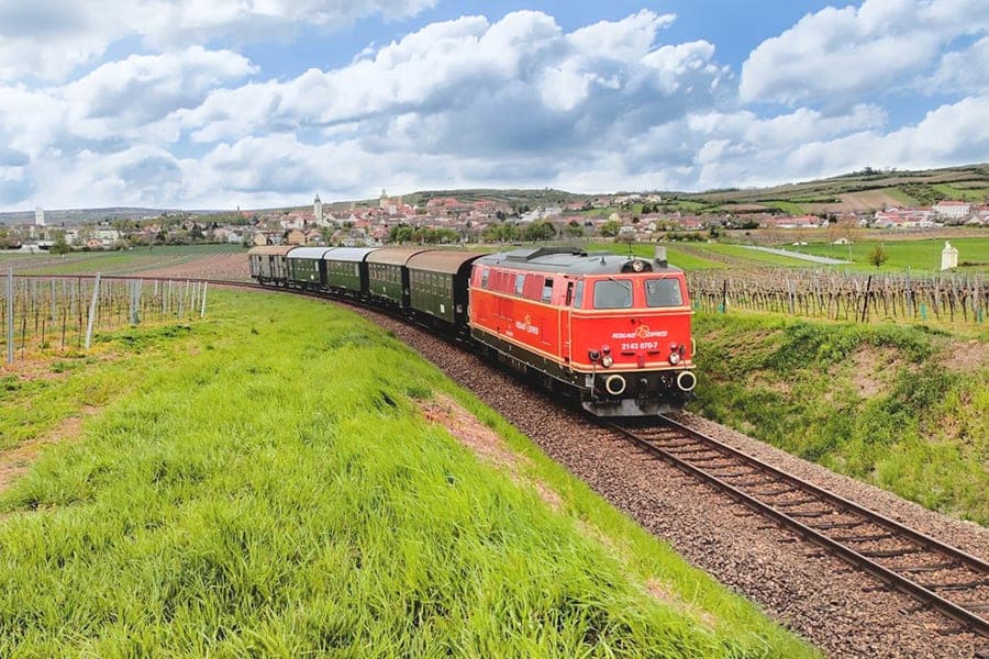 Reblaus Express — červená lokomotiva s historickými vozy mezi vinicemi