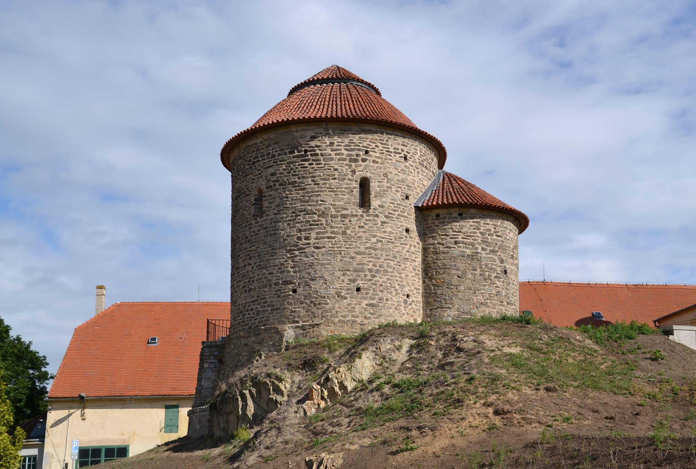 Rotunda sv. Kateřiny s kuželovou taškovou střechou na travnatém návrší nad Znojmem