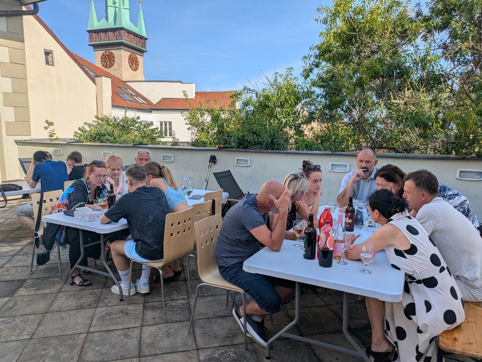 Posezení u stolů na střešní terase, v pozadí radniční věž