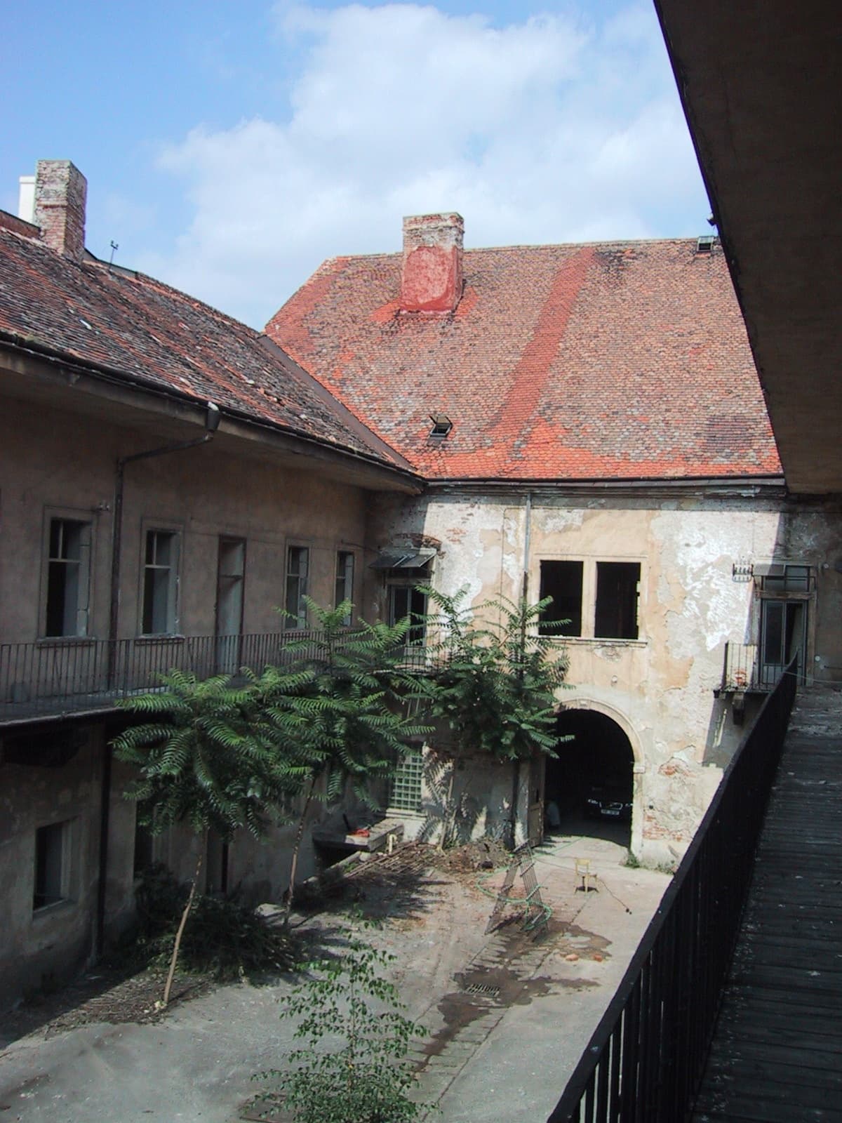 Nádvoří Althanského paláce před rekonstrukcí — opadaná omítka, náletové dřeviny a sutiny