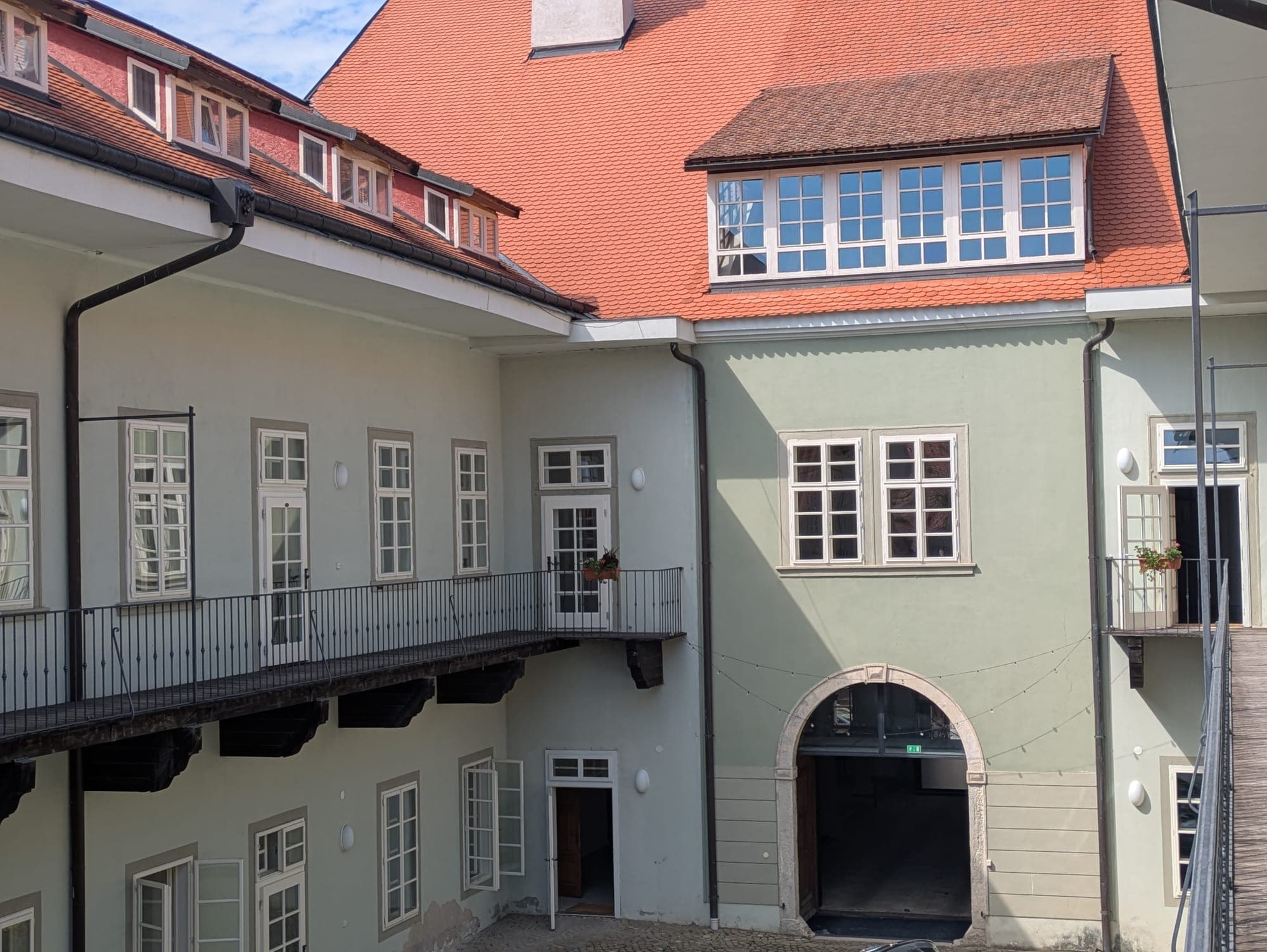 Totéž nádvoří dnes z pavlače — opravené fasády, nová střecha, dřevěné pavlače a klenutý průjezd