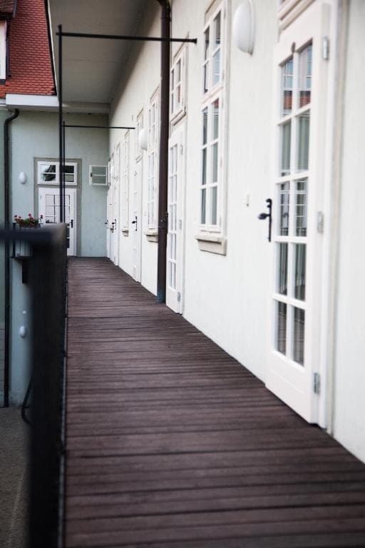 Dřevěná pavlač s bílými dveřmi do pokojů