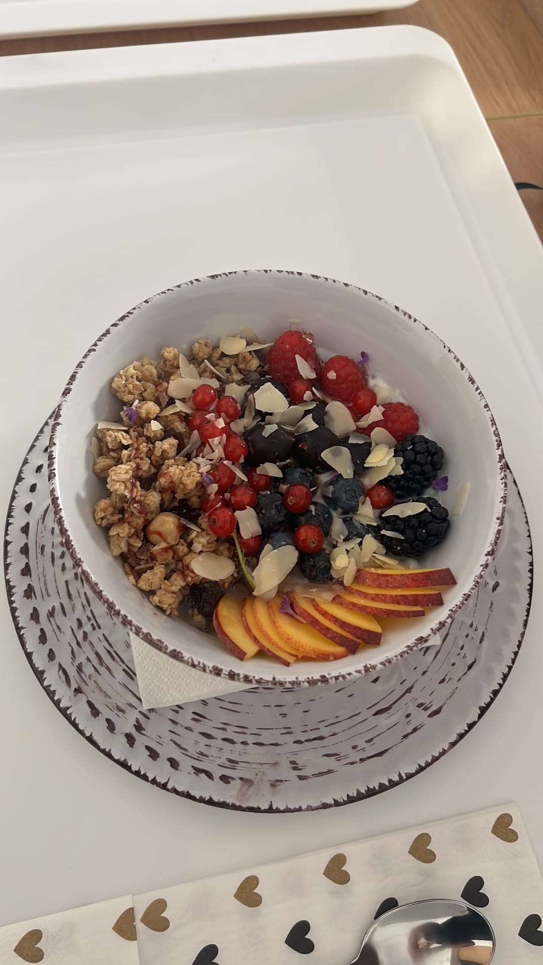 Eine Schale Granola mit Joghurt, Waldbeeren, Mandelblättchen und Nektarine